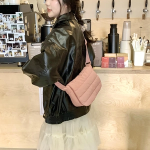 Detail view of a pink quilted crossbody bag with adjustable wide strap in casual setting