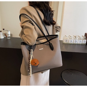 Detail of grey textured PU leather tote bag with brown plush bear charm and dual straps