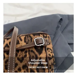 Detalle de bolso leopardo con correa ajustable de cuero marrón y hebilla plateada