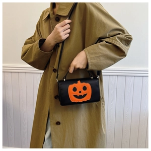 Detail of black PU leather bag with orange pumpkin face patch worn over a khaki trench coat