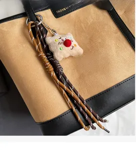 Detailed close-up of fashion plush doll pendant and woven ropes on leather tote bag