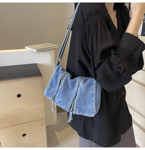 Detailed side view of washed denim crossbody bag featuring triple front metal zippers