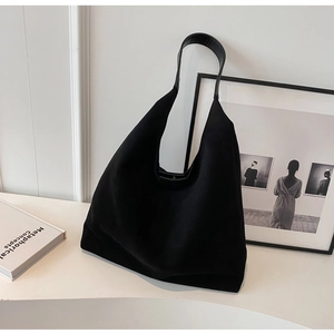 Detail of a large black fabric hobo bag with leather straps on a minimalist background
