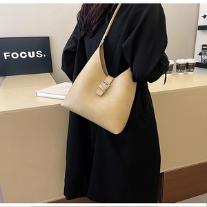 Détail du sac à bandoulière en similicuir beige avec coutures irrégulières et boucle argentée