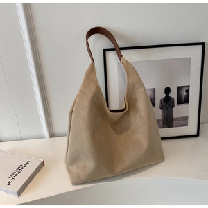 Macro shot of minimalist beige suede tote bag with brown leather handles in a chic room
