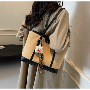 Detail view of large beige tote bag with black leather trim and cute bear charm pendant