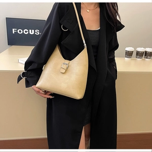 Détail du grand sac cabas en cuir PU beige avec boucle argentée sur un manteau élégant