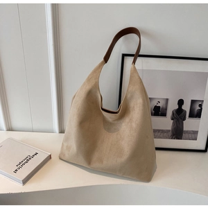 Detail of soft khaki suede tote bag with brown leather handle on minimalist background