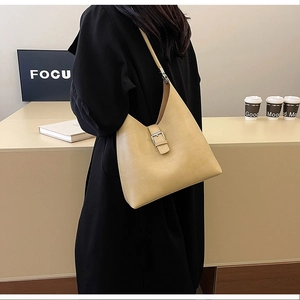 Détail d'un sac à bandoulière en cuir PU beige avec coutures géométriques et boucle argent