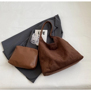 Detail of dark brown suede tote bag and matching pouch on a grey suit with LIFE book