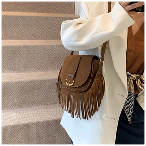Close-up of brown suede saddle bag with long fringes and gold metal buckle detail