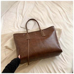Chic caramel brown PU leather tote bag with geometric stitching on soft white fabric