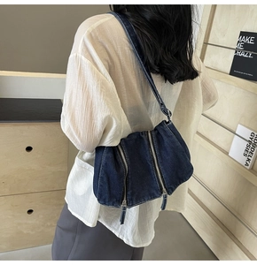 Detail of dark blue denim shoulder bag featuring trendy dual vertical metal zippers
