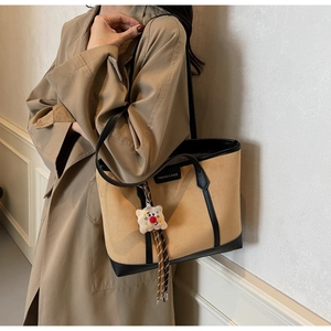 Detail of khaki canvas tote with black leather trim and cute white teddy bear charm