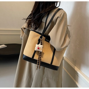 Detailed view of bicolor PU leather tote bag with a cute plush bear charm on the strap