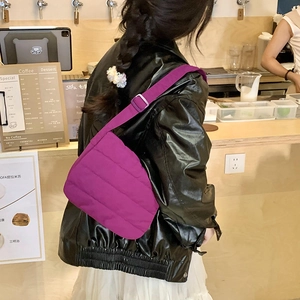 Detailed close-up of a purple quilted nylon puffer shoulder bag in a cafe setting