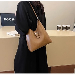 Détail d'un sac à bandoulière en cuir PU caramel avec surpiqûres et boucle argentée