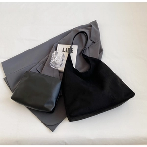 Detail of black suede hobo tote with matching smooth leather zipper pouch on grey blazer