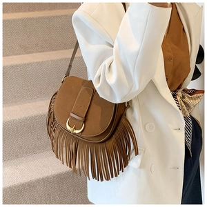 Detail shot of brown matte PU saddle bag featuring long tassels and gold metal buckle