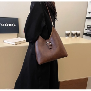 Gros plan détaillé du sac à bandoulière en cuir PU marron avec boucle métal et texture treillis