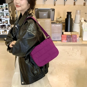 Detailed view of the bright purple quilted puffer bag on model in a casual cafe setting