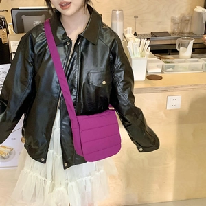 Lifestyle shot of a purple quilted crossbody bag styled with a leather jacket in a cafe