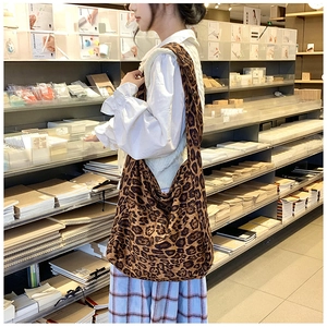 Detailed view of large leopard print canvas hobo bag worn over the shoulder