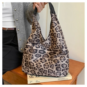 Détail d'un grand sac hobo à motif léopard avec des poignées en cuir noir sur une table