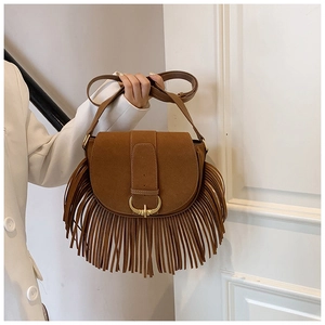 Detail view of brown matte suede crossbody bag with golden buckle and fringed tassels