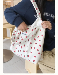 Gros plan sur un sac cabas en velours côtelé blanc avec motifs fraises et étiquette