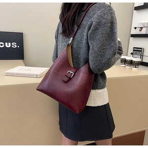 Sac fourre-tout bordeaux en similicuir avec coutures géométriques porté par un mannequin