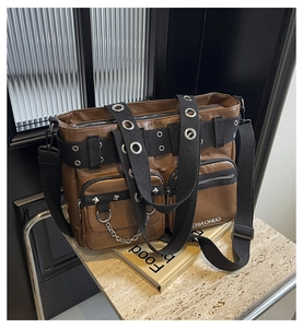 Detail of brown PU leather bag with multi-pockets, black webbing straps and metal rivets