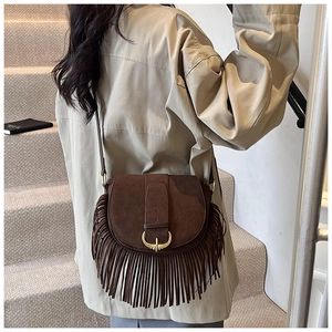 Detail of vintage brown suede crossbody bag with long fringes and golden horseshoe buckle