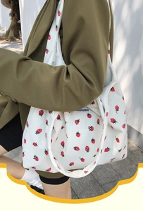 Détail du sac cabas en velours côtelé avec imprimé fraise rouge et étiquette de marque