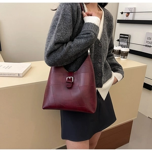 Détail du sac à bandoulière en cuir PU rouge foncé avec coutures et boucle argentée