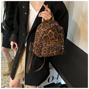 Detalle de una mochila pequeña de leopardo con cremalleras dobles y correas finas marrones