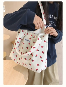 Détail du sac fourre-tout en velours blanc avec imprimé fraise et écusson du logo