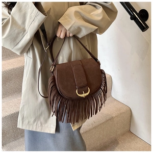 Close-up of brown suede crossbody bag featuring long bohemian tassels and a gold U-buckle