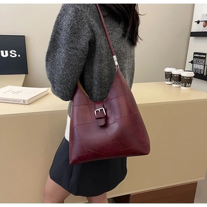 Détail du sac bandoulière en similicuir bordeaux avec coutures géométriques et boucle