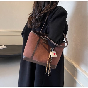 Close-up of caramel suede tote bag featuring brown leather trim and fashion logo detail