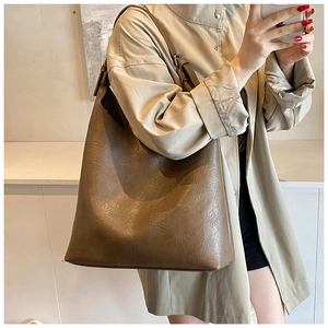 Detailed view of brown large capacity PU leather tote bag worn with a beige trench coat
