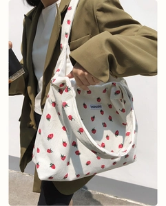 Détails de la texture du sac en velours côtelé avec motifs fraises rouges et large bandoulière