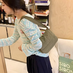 Detailed view of olive green quilted shoulder bag with horizontal padded texture