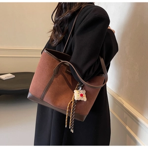 Brown faux suede tote bag with leather contrast and plush bear charm worn on the shoulder