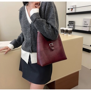Détail d'un sac cabas bordeaux en similicuir avec design patchwork et boucle en métal