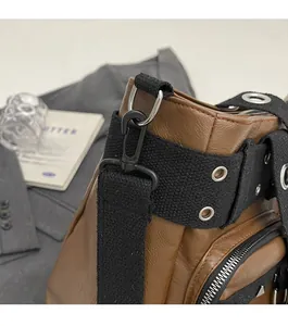 Detail of a brown PU leather bag showing a sturdy metal swivel hook and canvas strap