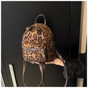 Detalle de mini mochila con estampado de leopardo, correa de cuero marrón y cierres plateados