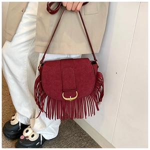 Close-up of wine red matte saddle bag with long fringes and golden horn buckle detail
