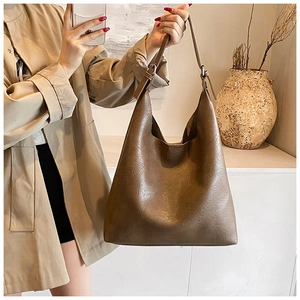 Close-up of brown PU leather tote bag texture with adjustable metal buckle strap details