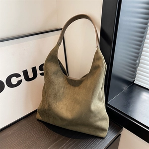 Olive green suede tote bag with brown leather shoulder strap in a minimalist setting
